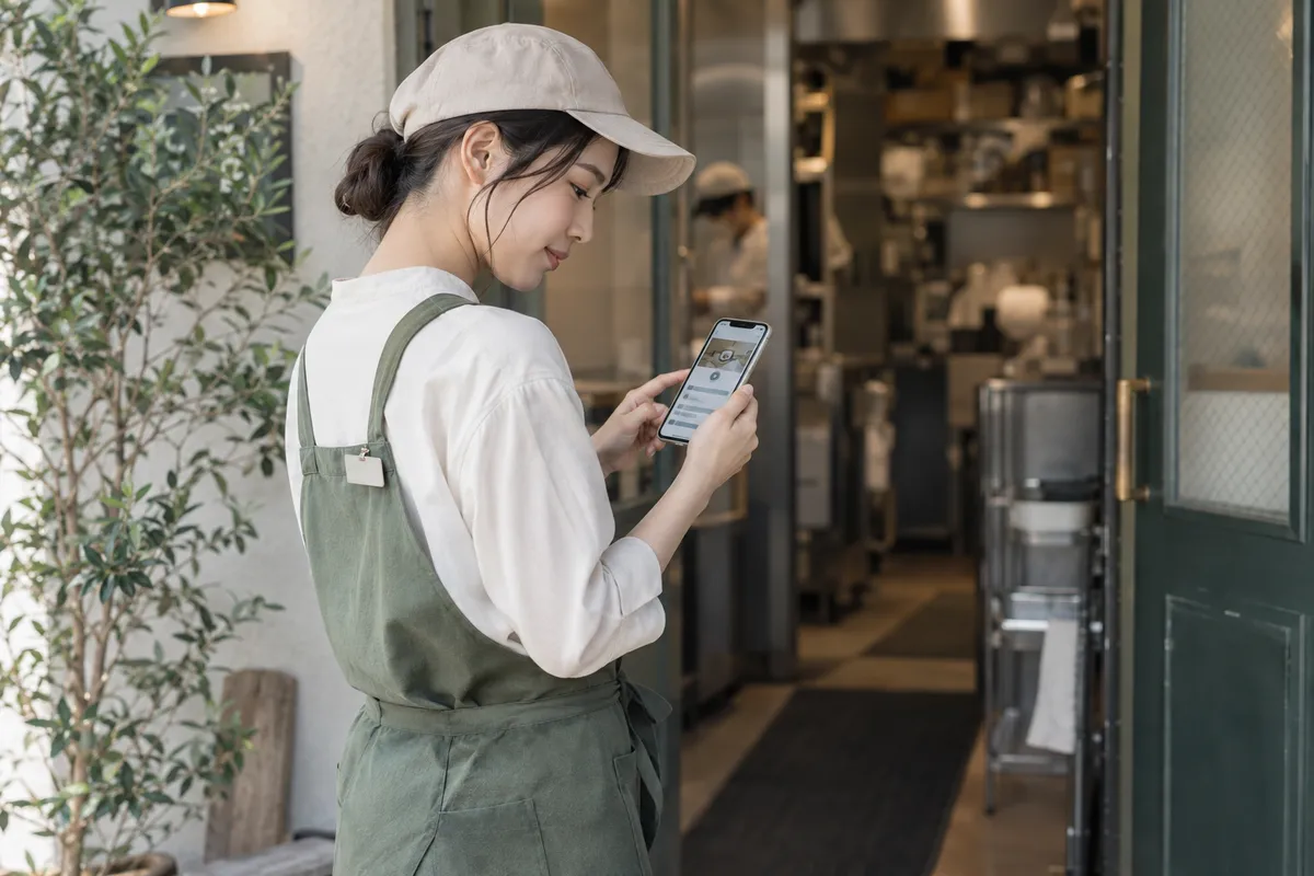 勤務の前に、店の入口でスマホの教材を確かめる新人スタッフ